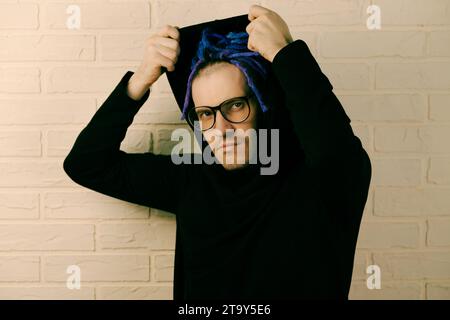 Der lebendige Mann mit markanten lila Dreadlocks und einzigartigem Style zieht eine Kapuze an. Stockfoto