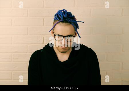 Ein Mann mit leuchtenden lila Dreadlocks und einem eleganten schwarzen Hoodie. Stockfoto