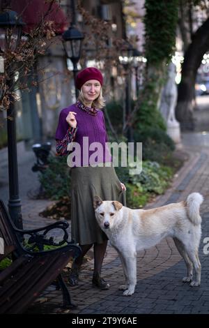 Eine Frau steht auf der Straße mit einem streunenden Hund. Stockfoto