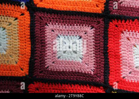 Nahaufnahme einer kastanienbraunen, orange und rot gehäkelten Wolldecke Stockfoto