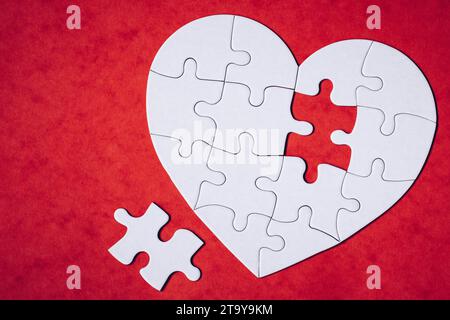 Heart-shaped Puzzle auf farbigen Hintergrund. Puzzle Herz auf Holz- Hintergrund. Ein fehlendes Stück des Herzens Puzzle. Herz Puzzle. Puz Stockfoto