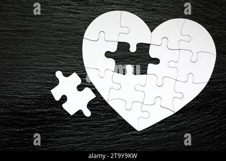 Heart-shaped Puzzle auf farbigen Hintergrund. Puzzle Herz auf Holz- Hintergrund. Ein fehlendes Stück des Herzens Puzzle. Herz Puzzle. Puz Stockfoto