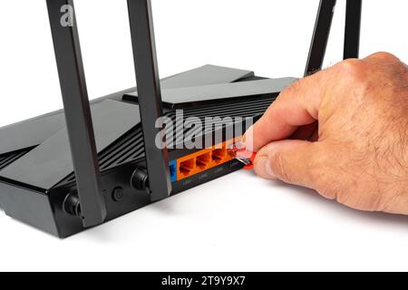 Die Hand des Mannes verbindet das Internetkabel mit dem wlan-Router Stockfoto