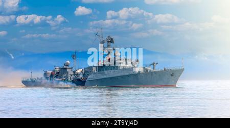 Das russische Kriegsschiff, das die Küste des Pazifischen Ozeans bei sanftem Sonnenlicht entlang fährt Stockfoto