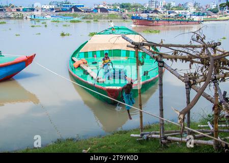 Traditionelle Frachtbootstation am Ufer. Eine malerische Szene entfaltet sich entlang des Flusses von Bangladesch, während traditionelle Frachtschiffe Th finden Stockfoto