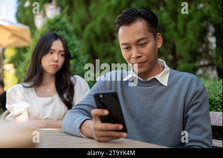 Eine junge asiatische Freundin, die sich über ihren Freund ärgert, weil sie ihr nicht aufgepasst hat. Paarungskonzept. Stockfoto
