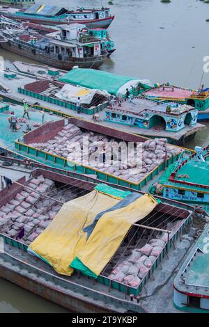 Traditionelle Frachtbootstation am Ufer. Eine malerische Szene entfaltet sich entlang des Flusses von Bangladesch, während traditionelle Frachtschiffe Th finden Stockfoto