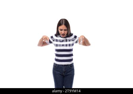 Eine junge europäische Dame mit schwarzen, gleichmäßigen Haaren in einem gestreiften T-Shirt zeigt mit ihrem Zeigefinger auf Ideen und Nachrichten Stockfoto