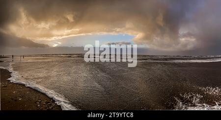 Goldenes Sonnenlicht, tief hängende Regenwolken und eintretende Flut an einem dezembernachmittag an der Nordseeküste auf der Insel Rømø Stockfoto