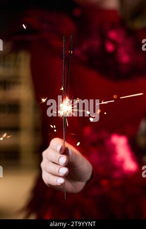 Ein Mädchen in einem eleganten roten Kleid hält Glitzer in den Händen Stockfoto