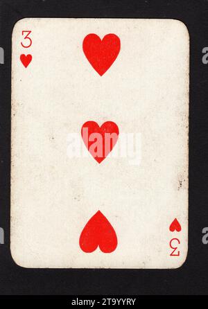 Eine Vintage-drei-Herzen-Spielkarte isoliert auf schwarzem Hintergrund. Stockfoto