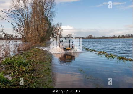 Ein Auto, das aufgrund von starkem Regen und Windfaktor durch eine überflutete Straße gefahren wird. Das nationale Koordinierungskomitee für Hochwassergefahr (LCO) des Rijkswaterstaates trat am Donnerstag aufgrund der erwarteten hohen Wasserstände an der Küste, am IJsselmeer und an den großen Flüssen in Aktion. Eine solche Situation ist laut Rijkswaterstaat selten. Die Sturmflut-Barrieren Hollandse IJsselkering in Zuid-Holland und die Haringvlietsluizen werden am Donnerstagabend geschlossen. Das Ramspolkering in der IJssel bei Kampen wird wahrscheinlich später geschlossen. Das Wasser entlang der Küste wird von starken Winden hochgetrieben. Das KNM Stockfoto