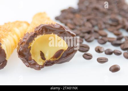 Köstliches sizilianisches Cannolo Cannellino süß mit Gebäck Haselnussschokolade und Gebäck Creme in der Nähe von Kaffeebohnen, italienisches Blätterteig auf weißem Hintergrund, Ernährungs- und Diätkonzept Stockfoto