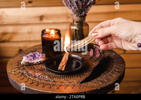 Frauenhände halten und verwenden Palo Santo Holz Sticks Rauch für die Hausreinigung von alter negativer Energie. Ölige aromatische heilige Holzstäbchen Stockfoto