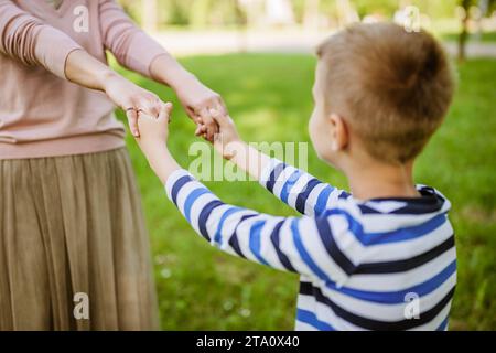Glückliche Mutter spielt mit ihrem Sohn im Park. Sie halten Händchen. Stockfoto