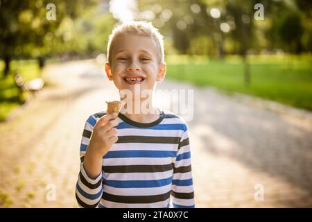 Porträt eines glücklichen Jungen, der im Park steht und Eis isst. Stockfoto