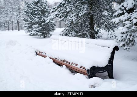 Schneebedeckter Park mit einer im Schnee vergrabenen Bank Stockfoto