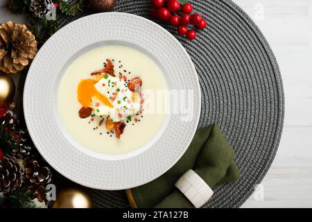 Pochiertes Ei mit Kartoffelcreme und Pilzen. Weihnachtsessen werden auf einem Tisch serviert, der mit Weihnachtsmotiven dekoriert ist. Stockfoto