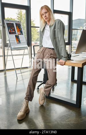 Vertikale Aufnahme einer ansprechenden, langhaarigen, nicht binären Person in Business-Freizeitkleidung, die in die Kamera schaut Stockfoto