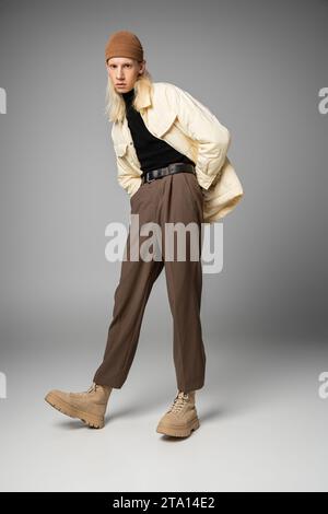 Vertikaler Schuss eines jungen attraktiven, nicht binären Menschen in trendiger Winterkleidung mit Händen in den Taschen Stockfoto