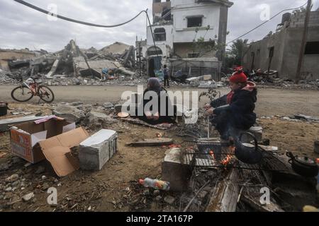 Khan Yunis, Palästinensische Gebiete. November 2023. Während des vorübergehenden Waffenstillstands zwischen Israel und der Hamas sitzen Palästinenser um die Zerstörung im Dorf Khuza·a in der Nähe des Grenzzauns zwischen Israel und dem südlichen Gazastreifen. Quelle: Mohammed Talatene/dpa/Alamy Live News Stockfoto