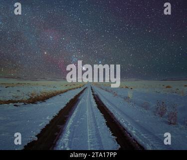 Nächtliche Landschaft mit einer schneebedeckten Feldstraße und dem Sternbild Orion im Lassen County Kalifornien, USA. Stockfoto