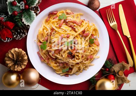 Spaghetti Carbonara. Weihnachtsessen werden auf einem Tisch serviert, der mit Weihnachtsmotiven dekoriert ist. Stockfoto
