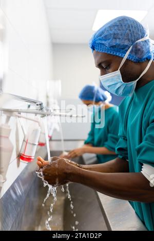 Diverse männliche und weibliche Chirurgen mit Gesichtsmasken beim Händewaschen im Krankenhaus Stockfoto