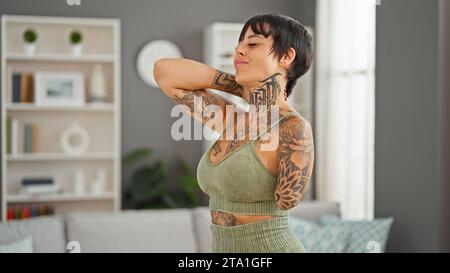 Hispanische Frau mit amputiertem Arm in Sportbekleidung, die zu Hause an Gebärmutterhalsschmerzen leidet Stockfoto