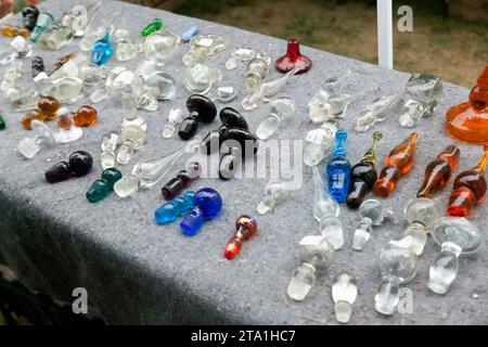 Nahaufnahme einer Reihe von farbigen und flachen Glasstopfen, zum Verkauf auf dem Brimfield Flea Market, Hampden County, Massachusetts, Stockfoto