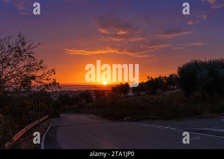 Landstraße nach Tortoreto an der Adria in den Abruzzen mit einem farbenfrohen Sonnenaufgangshimmel über dem Meer Stockfoto