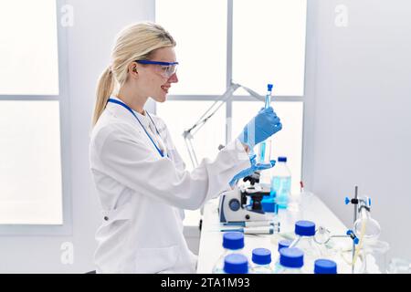 Junge blonde Wissenschaftlerin, die Reagenzgläser im Labor analysiert Stockfoto