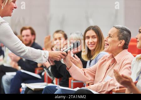 Redner fragte glückliche Geschäftsfrau während einer Geschäftskonferenz im Convention Center Stockfoto