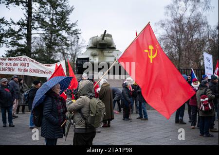 25.11.2023, Berlin, Deutschland, Europa - im Vorfeld einer Friedensdemonstration steht ein Demonstrant mit roter sowjetischer Flagge am Sowjetischen Ehrenmal im Ortsteil Tiergarten mit einem T-34 Panzer im Hintergrund. Einige tausend Menschen demonstrieren am Brandenburger Tor im Berliner Bezirk Mitte für den Frieden unter dem Titel Nein zu Kriegen- Ruestungswahnsinn stoppen - Zukunft friedlich und gerecht gestalten . Eine der zentralen Forderungen der Kundgebung sind Verhandlungen mit Russland. Auf der Demonstration sprachen neben der Hauptrednerin und ehemaligen Linken-Politikerin Sahra Wag Stockfoto