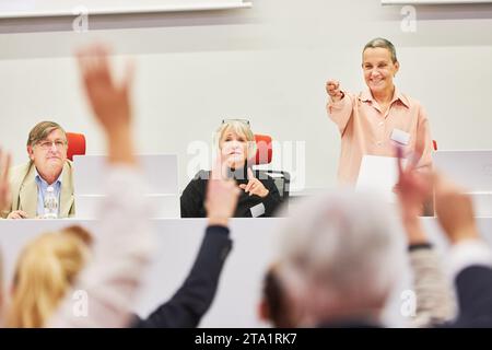 Weibliche Spekaer auf der Konferenz, die Fragen von erhobenen Händen von Menschen im Publikum beantwortet Stockfoto