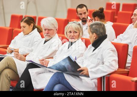 Ärztinnen diskutieren über Röntgenaufnahmen, während sie während der Konferenz im Publikum sitzen Stockfoto