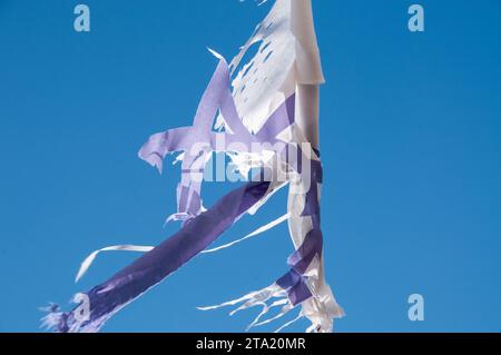 Abgenutzte und verwitterte, zerrissene und zerrissene Reste einer israelischen Flagge flattern an sonnigen Tagen im Wind. Stockfoto