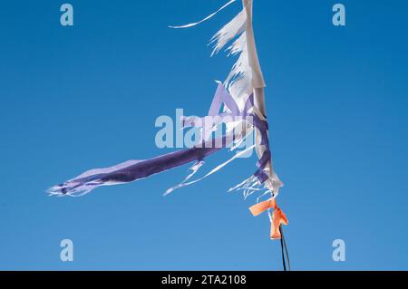 Abgenutzte und verwitterte, zerrissene und zerrissene Reste einer israelischen Flagge flattern an sonnigen Tagen im Wind. Stockfoto