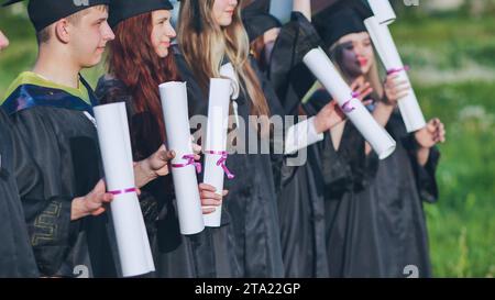 Scrollt Diplome in den Händen einer Gruppe von Absolventen. Stockfoto