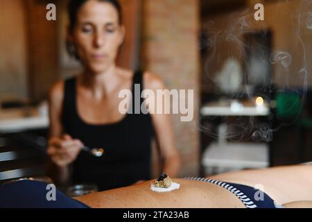 Therapeut wenden Bauchmoxibustion chinesische Medizin brennen Beifuß Moxa Rauchen Kegel Akupunktur Punkt 50s kaukasische fit Frau, Bauch Bauch Stockfoto