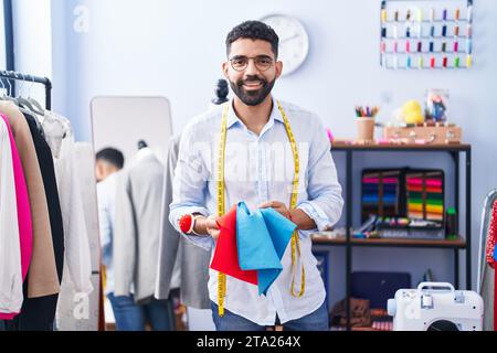 Junger arabischer Schneidermann lächelt selbstbewusst in der Schneiderei Stockfoto