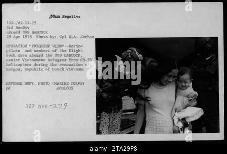 Marine-Piloten und Flugdeckbesatzung an Bord der USS Hancock unterstützen vietnamesische Flüchtlinge aus CH-53 Hubschraubern während der Evakuierung der Operation Frequent Wind am 29. April 1975. Stockfoto