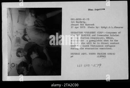 Korps an Bord der USS Hancock und Commander Rabalet von der Station Dispensary verabreichen Gamaglobulin-Schüsse an die Marines, um den Kontakt mit südvietnamesischen Flüchtlingen während der Operation Frequent Wind am 27. April 1975 vorzubereiten. Stockfoto