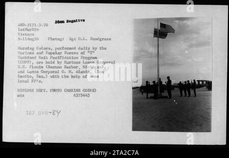 Marines und Popular Forces des „T“ Combined Unit Pacification Program (CUPP) nehmen am 9. August 1970 an der Morning Colors Zeremonie in Vietnam Teil. Die Lance Corporals T.H. Fionie und G.M. Alaniz halten die amerikanische Flagge während der Zeremonie. Dieses Foto wurde von Sergeant O.L. Snodgrass aufgenommen und ist Teil der Sammlung des US-Verteidigungsministeriums. Stockfoto