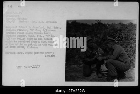 Corporal Robert L. Craford, Squad Leader of Weapons Platoon, 'E' Company, 2/3 Marines, wird zusammen mit dem privaten First Class Thomas Lavin, einem Maschinenschützer desselben Platoons, gezeigt. Lavins Helm zeigt ein Schussloch, das ein Scharfschütze während einer Patrouille im Dorf XUAN DEUNG in Vietnam zugefügt hat. Dieses Bild wurde von Sergeant R.R. Reynolds am 4. Mai 1965 aufgenommen. Stockfoto