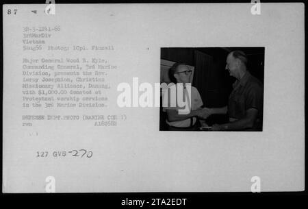 Major General Wood B. Kyle, Commanding General der 3. Marine Division, überreicht Reverend Leroy Josephion von der Christian Missionary Alliance, Danang, eine Spende von $1.000,00. Das Geld wurde während protestantischer Gottesdienste in der 3. Marine Division gespendet. Dieses Foto wurde am 5. August 1966 aufgenommen.-(135) Stockfoto