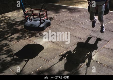 Unerkanntes Kind, das Spaß auf einer Schaukel auf einem Spielplatz hat. Menschen, die im Freien aktiv sind. Gesunder Lebensstil Stockfoto