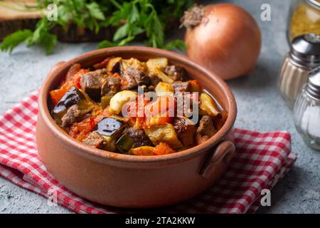 Draufsicht auf das türkische Gericht Guvech - gebackenes Fleisch mit Auberginen und traditionell in Steinguttopf serviert (türkischer Name; etli patlican guvec) Stockfoto