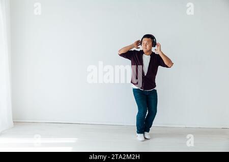 Ein Mann hört Musik mit Kopfhörern und tanzt in einem hellen Raum Stockfoto