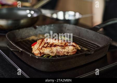 Nahaufnahme des gekochten Steaks in der Grillpfanne mit Kräutern, Schwerpunkt auf Fleisch Stockfoto